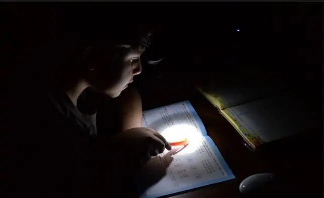 Мальчик делает уроки с фонариком. Фото 123ru.net.