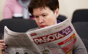 Женщина читает газету с вакансиями о работе. Фото Кирилла Зыкова / АГН "Москва"