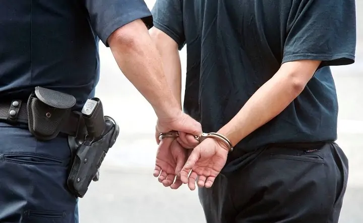 Полицейский ведёт задержанного в наручниках. Фото riafan.ru