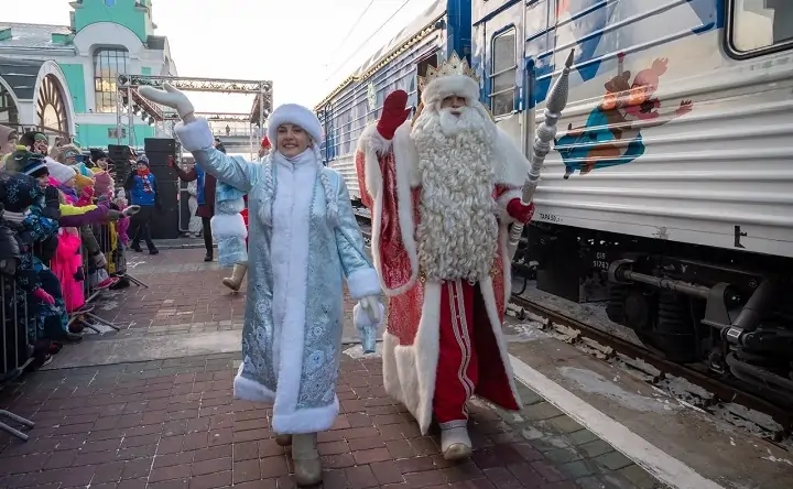 Дед Мороз и Снегурочка идут по перрону вокзала. Фото poezddedamoroza.ru