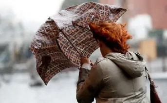 Сильный ветер сбивает женщину с ног. Фото ТАСС