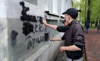Неравнодушные граждане закрашивает рекламу наркотиков на стене жилого дома. Фото ako.ru