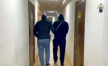 Задержанного мужчину ведут по коридору следственного отдела. Фото регионального Следкома