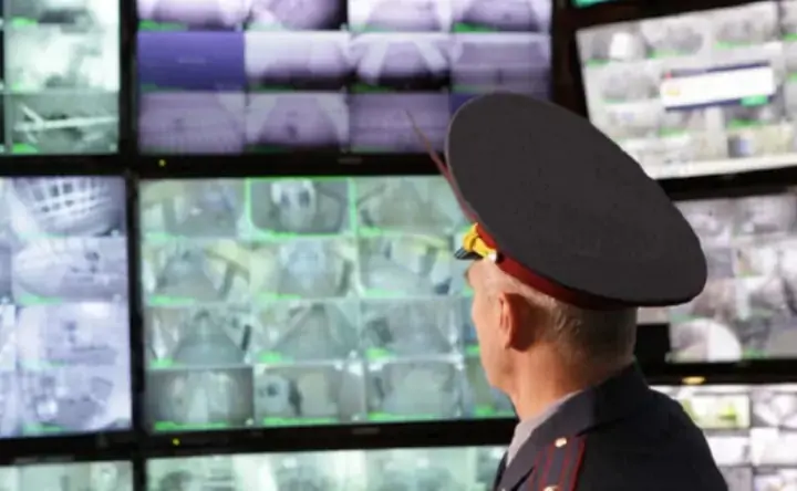 Полицейский смотрит в камеры видеонаблюдения. Фото vedomosti.ru