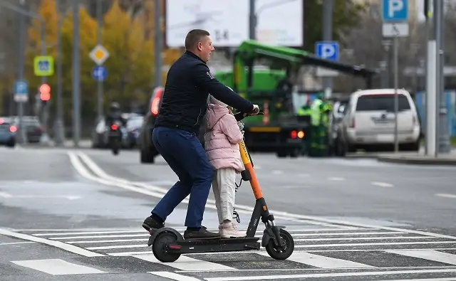 Мужчина с ребёнком едут на электросамокате. Фото Кирилла Каллиникова / РИА Новости